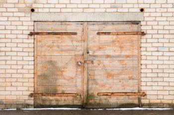 Old weathered wooden garage door locked with padlock