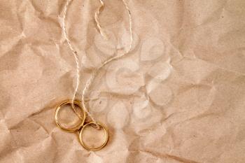 Two gold wedding rings tied with string over paper background