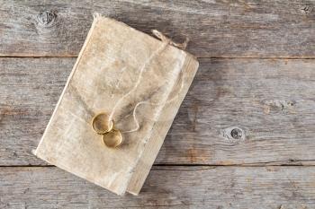 Two wedding rings with a bible on wooden background
