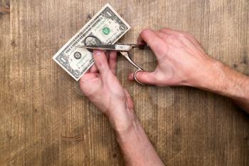 Hand holding scissors cutting US Dollar banknote, cut budget, reduce cost 