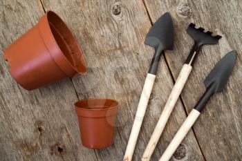 Gardening tools with dirty pots on wood background