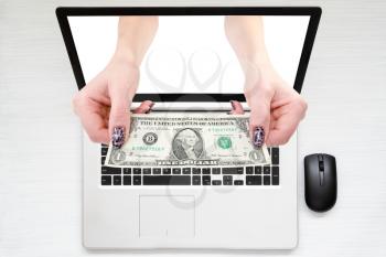 Women hands with money comes from laptop screen