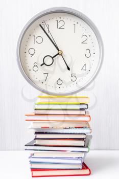Wall clock on top of a stack of  books 