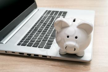 Piggy bank on laptop keyboard in money saving concept. Make money online or internet business concepts