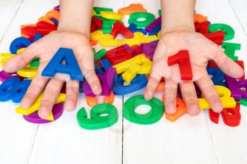 Girl learning using magnetic letters and numbers. Education School Concept
