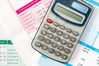 Financial office salary or tax calculation concept by calculator on pile of salary slips