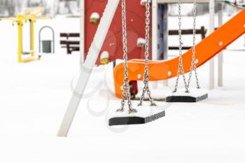 Empty swing in winter time with snow.Children playground in winter after snowfall