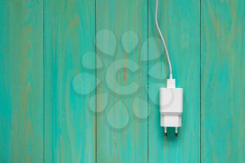 White smartphone charger over blue wooden background. Copy-space.
