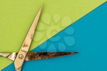 Metal scissors on green and blue paper background