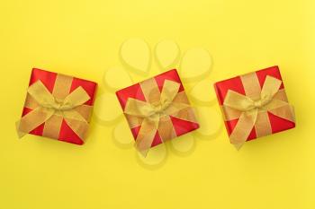 Three Gift boxes with golden bows on yellow background. Top view.