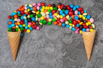   Waffle horns with colored candy on a stone background. Top view, copy-space.