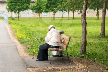 Lonely senior woman with a cane sitting on a bench