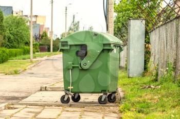 Green garbage container standing on the street 