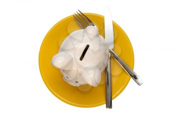 Savings consumer concept. Piggy bank on the yellow plate with fork and knife,isolated on white