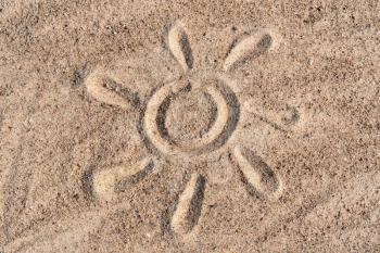 Simple sun drawing in the sand on the beach