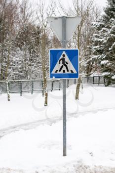 Pedestrian crossing road sign with snow. Safe driving in winter time.