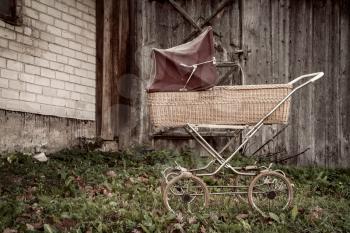 Retro style stroller baby carriage outdoors on old building background