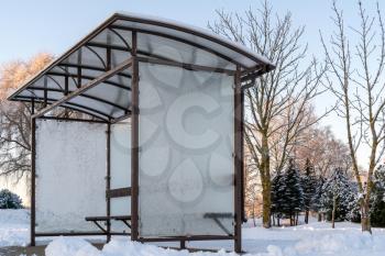 Small empty bus stop with frozen glass in a winter morning