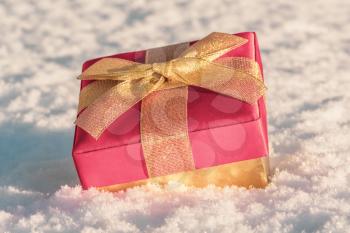 Christmas gift box with gold ribbon in a fresh snow 