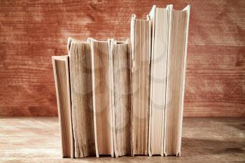 Old books stacked in a row on wooden background