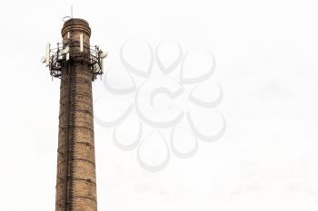 Old brick chimney with  antennas on cloudy sky background