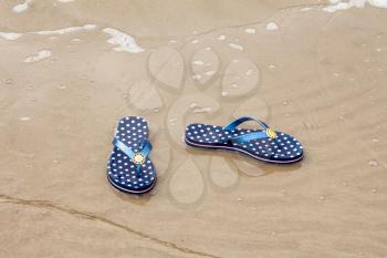 Sandal flip-flops lying on the seashore near the water