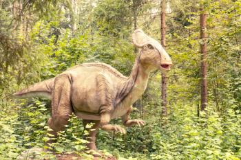 Statue of a real looking dinosaur in a green forest