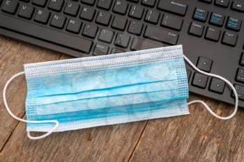 Surgical mask are placed on  computer keyboard, while you are trying to find more of them online by browsing the Internet.Unfortunately they are all sold out, because of new virus.
