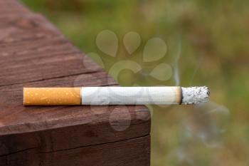 Close up of a cigarette on the bench in public place