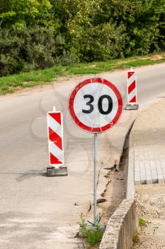 Warning of the road works which are ahead. The speed limit sign with the number 30