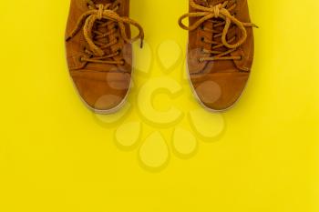  Brown leather sneakers  on yellow background. Top view.