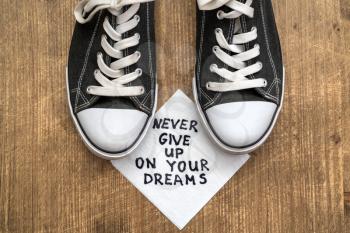 Never Give Up On Your Dreams - handwriting on a napkin with a old sneakers