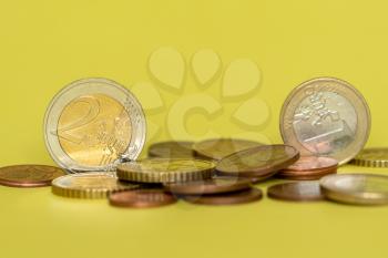 Euro coins in pile on yellow background