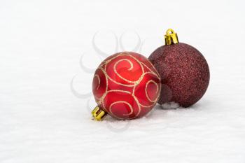 Red Christmas baubles lying in the snow. Holiday background