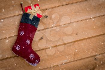 Christmas stocking full of gifts hanging on wooden wall in a snowy weather