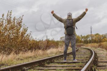 Man standing on the railway and raising hands up. Rear view.