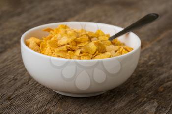 Bowl with cornflakes on dark wooden background