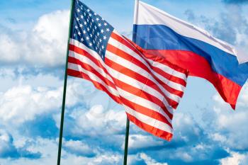 Flags of the USA and Russia against the background of the cloudy sky