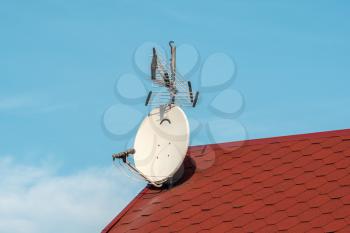 Satellite dish and TV antennas on the house roof 