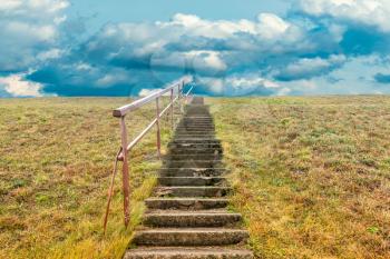 A stone staircase rises in the cloudy sky. The concept of stairway to heaven.The concept of growth up.