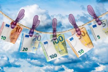 Euro banknotes on a clothesline against cloudy sky