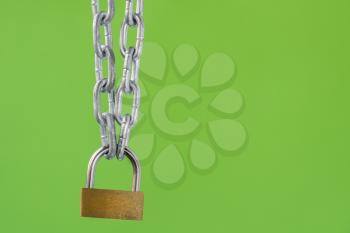 Padlock with metal chain on a green background