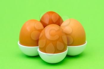 A cell with brown round chicken eggs on the green background