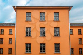Facade of orange industrial building with cloudy sky background