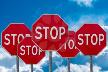 Stop Signs Against Cloudy Blue Sky Background