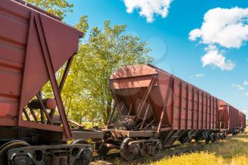 Railway containers with bulk materials. The locomotive pulls a large freight train. Summer sunny day.