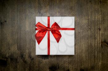 Gift white box with a red bow on a dark wooden background. Valentine's Day, Christmas, Birthday, Mother's Day.