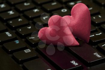 Two hearts on the black computer keyboard. Internet dating concept