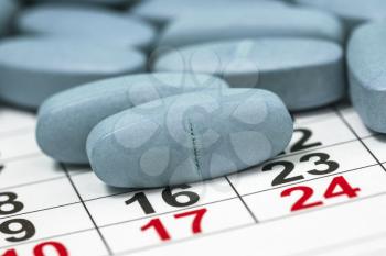 Blue medical pills on a monthly calendar. Medication plan, schedule, list or calendar concept.