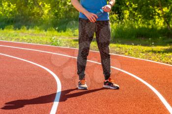 Runner with water bottle on athletic track. Healthy lifestyle.